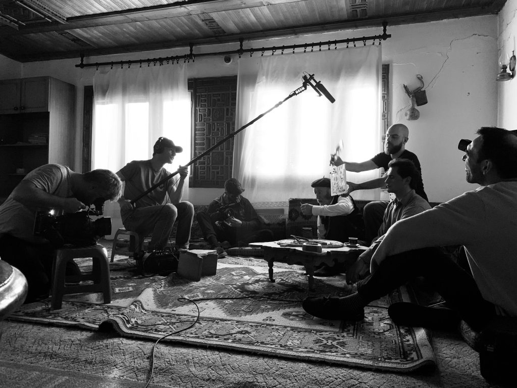 Film crew working indoors on a video shoot, capturing behind-the-scenes action.